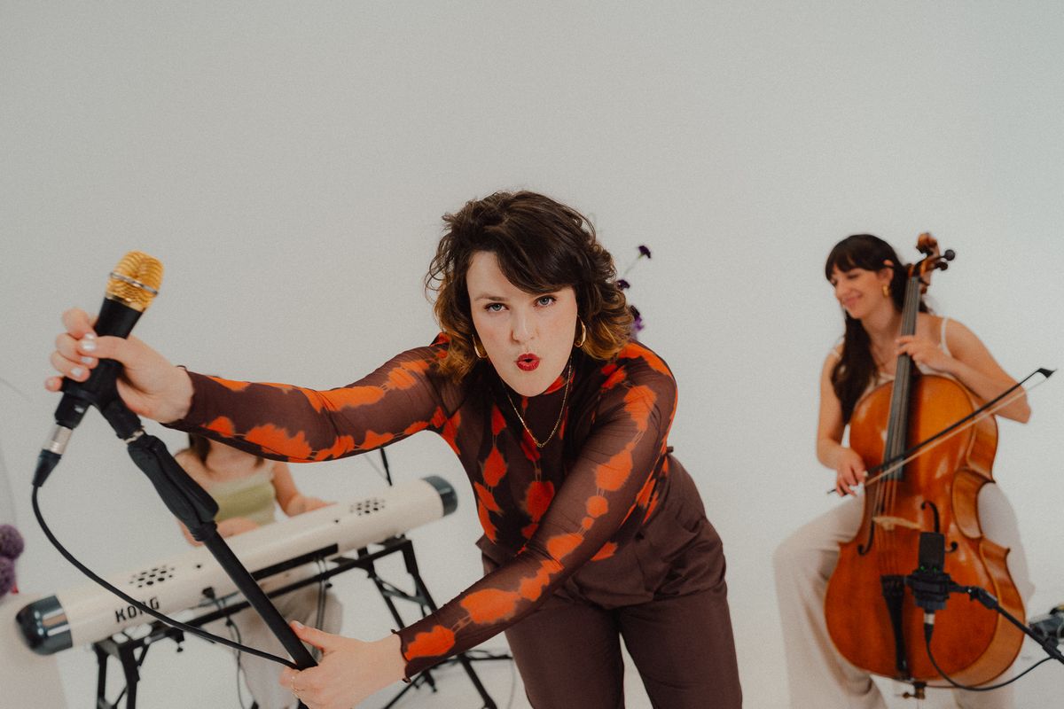 AVA singt mit dem Mikrofon in der Hand, neben ihr die Cellistin